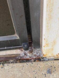 Bottom broken door pivot requires commercial door repair company to replace it